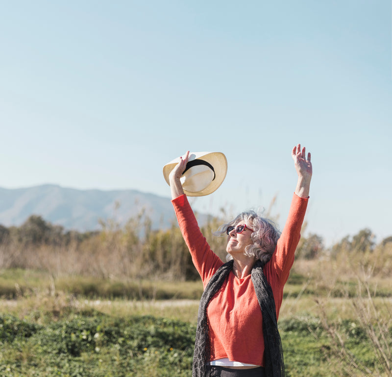 Older woman outdoors stretching with arms raised